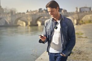 Joven con celular en la mano, busca los Primeros Trámites de Residencia española